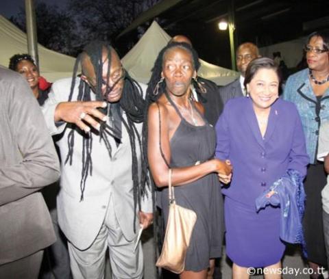 CLOWNING AROUND: Prime Minister Kamla Persad-Bissessar (right) laughs as Community Development Minister Winston 'Gypsy' Peters playfully 'wears' the dreadlocks of well-known community activist Christine 'Twiggy' Levia, centre, at yesterday's Hoop of Life awards ceremony at the St Barbs Basketball courts in Laventille.