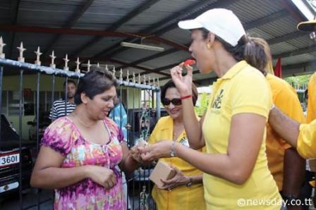 UNC candidate for the Chaguanas West bye election, Khadijah Ameen, right, tastes a piece of red mango offered by a constituent during a walkabout in Felicity yesterday. At centre is Prime Minister Kamla-Persad Bissessar who joined Ameen as she started her campaign for the July 29 bye-election yesterday. Author: Vashti Singh
