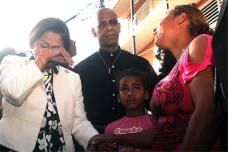 Prime Minister Kamla Persad-Bissessar, left, sheds a tear as she chats with Natasha Rogers, right, and her daughter, Narisha, at Duncan Street, Port-of-Spain, yesterday. Rogers’ son, Niam Antoine, was killed on Wednesday. At centre is Rodger Samuel, Arima MP. Photo: ANDY HYPOLITE