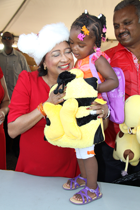 Prime Minister Kamla Persad-Bissessar is hugged and kissed by Kaaya Williams after she received her toy at the Prime Minister’s Annual Christmas Toy Drive at the Ato Boldon Stadium, Couva, yesterday. PHOTO: KRISTIAN DE SILVA