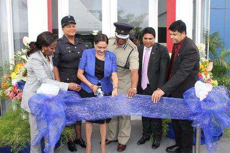 officially open: Prime Minister Kamla Persad-Bissessar, third left, cuts the ribbon to open the Piarco Police Station on Wednesday at Golden Grove Road, Piarco. Looking on from left are UdeCOTT managing director Jerlean John, acting sergeant Jennifer Crawford, acting Police Commissioner Stephen Williams, Housing Minister Dr Roodal Moonilal and Legal Affairs Minister Prakash Ramadhar. —Photo: STEPHEN DOOBAY