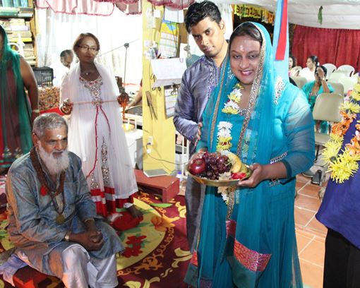 Couva North MP, Ramona Ramdial (right) proceeds to makes her offering at the Limehead Road Hindu Temple and is assisted by Pundit Mukram Sirju (left)