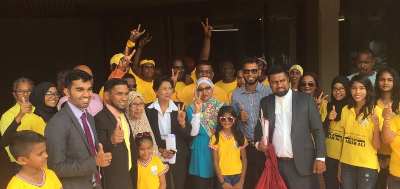 PHOTO -  Political Leader, Kamla Persad-Bissessar, SC together with attorney Saddam Hosein (from the left in grey suit), candidate Adrian Ali (dark suit and yellow tie), attorney Gerald Ramdeen (right) and UNC candidate Faaiq Mohammed (next to Gerald Ramdeen in blue shirt) celebrate with UNC supporters outside the Hall of Justice this morning (Sunday 27th November 2016)